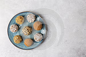 Homemade energy balls of dates, dried apricots, nuts and oatmeal on a round plate, view from above.