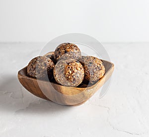 Homemade energy balls with dates, prunes, almonds. Healthy sweet food. Energy balls in a wooden bowl on a white background