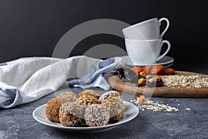 Homemade energy balls and ingredients for them on the table with cups on a dark background