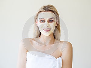Homemade facial beauty procedure. Enjoying and smiling woman with cream on her face looking into camera