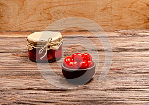 Homemade fermented pickled tomatoes in a brown bowl and glass jar on a wooden background