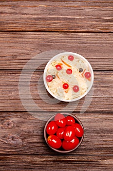 Homemade fermented pickled tomatoes and sauerkraut with cranberries on a wooden background