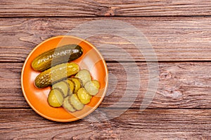 Homemade fermented pickles on a clay plate and on a wooden background. Copy space