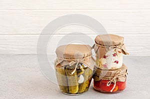 Homemade fermented products in glass jars - sauerkraut, pickled tomatoes, pickles, light gray background