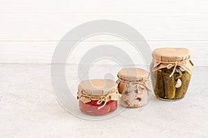 Homemade fermented products in glass jars - sauerkraut, pickled tomatoes, pickles, light gray background