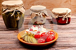 Homemade fermented products on a plate, sauerkraut, pickled tomatoes, pickles, wooden background