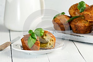 Homemade freefly baked double cheese muffins with basilic on a white wooden board. Healthy snack or breakfast meal.