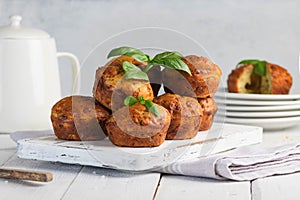 Homemade freefly baked double cheese muffins with basilic on a white wooden board. Healthy snack or breakfast meal.