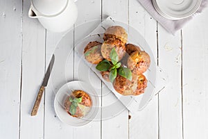 Homemade freefly baked double cheese muffins with basilic on a white wooden board. Healthy snack or breakfast meal. Concept of hea