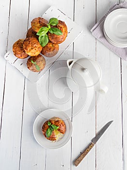 Homemade freefly baked double cheese muffins with basilic on a white wooden board. Healthy snack or breakfast meal. Concept of hea