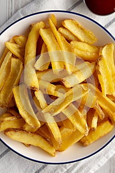 Homemade French Fries on a Plate on a white wooden background, top view. Close-up