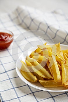 Homemade french fries with sour-sweet sauce on a white plate, side view. Close-up