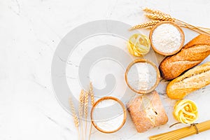 Homemade fresh bread and pasta near flour in bowl and wheat ears on white stone background top view copy space