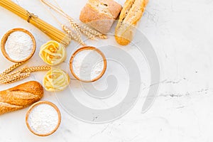 Homemade fresh bread and pasta near flour in bowl and wheat ears on white stone background top view space for text