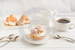 Homemade fresh cream puff with whipped cream and apricots, cup of coffee and milk jug. Toning.