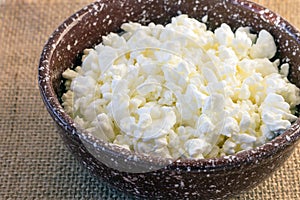 Homemade fresh crumbly delicious cottage cheese in a clay bowl.