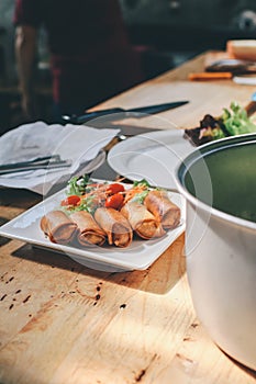 Homemade fresh Fried Chinese Traditional Spring rolls food with green salad and tomato in dish.