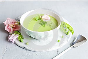 Homemade fresh green pea cream soup with pea sprouts and flowers