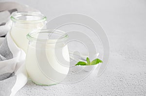 Homemade fresh organic yogurt in glass jars on a light background. Healthy food. Horizontal orientation.