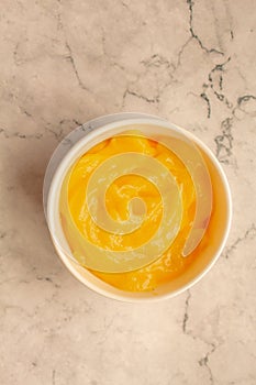 Homemade fresh pudding or tangy lemon curd in a white bowl on marble background.Top view