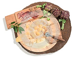 Homemade fresh ravioli with prosciutto,walnuts,brussels sprouts,artichoke and aromatic herbs paced on a rustic round centerpiece.