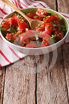 Homemade fresh tomato salad with herbs close up in a bowl. vertical