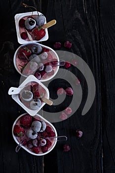 Homemade fresh yogurt. Healthy sweet dessert on dark rustic wood. Frozen fruits