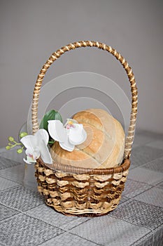 Homemade freshly baked bread is in a basket on the table. There are Orchid flowers next to it