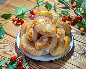 Homemade fried pies with cherry filling, green twigs with cherry berries in a blue ceramic vase