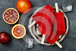 Homemade frozen blood orange natural juice alcoholic popsicles - paletas - ice pops. Overhead, flat lay, top view.