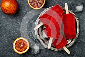 Homemade frozen blood orange natural juice alcoholic popsicles - paletas - ice pops. Overhead, flat lay, top view.