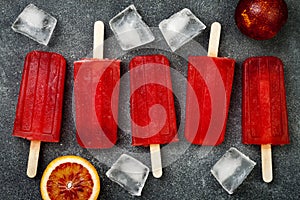 Homemade frozen blood orange natural juice alcoholic popsicles - paletas - ice pops. Overhead, flat lay, top view.