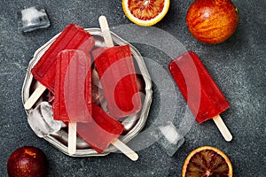 Homemade frozen blood orange natural juice alcoholic popsicles - paletas - ice pops. Overhead, flat lay, top view.