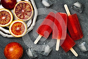 Homemade frozen blood orange natural juice alcoholic popsicles - paletas - ice pops. Overhead, flat lay, top view.