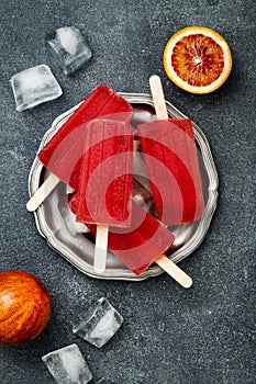 Homemade frozen blood orange natural juice alcoholic popsicles - paletas - ice pops. Overhead, flat lay, top view.