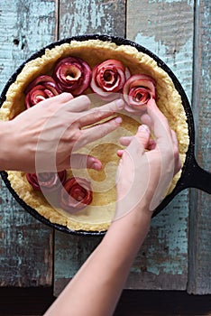 Homemade fruit pie. Woman hands making apple roses for pie in ca