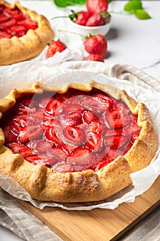 Homemade galettes with strawberries on white marble background