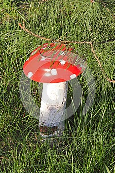 Homemade garden sculpture - mushroom amanita on the grass. The mushroom is made from an old plate and log.