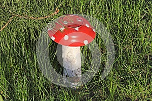 Homemade garden sculpture - mushroom amanita on the grass. The mushroom is made from an old plate and log.