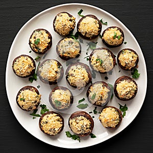 Homemade Garlic Parmesan-Stuffed Mushrooms on a plate on a black background, top view
