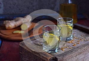 Homemade ginger tincture or ale on wooden background. Rustic style. Spice yellow liqueur in a glass. Alcohol drink.