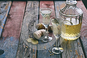 Homemade ginger tincture or ale on wooden background. Rustic style. Spice yellow liqueur in a glass. Alcohol drink.