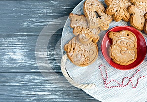 Homemade gingerbread cookies and red cup with coffee on tray on grunge gray wooden background. Christmas and New Year celebration