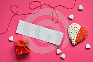 Homemade gingerbread hearts with an empty paper for your text on pink background. Valentine cookies hearts. Edible Valentines Da