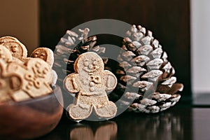 Homemade gingerbread man on a wooden table and pine cones at Christmas holidays