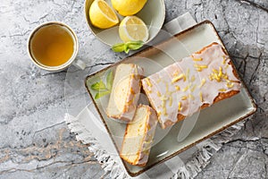 Homemade glazed lemon pound cake closeup on the plate served with tea. Horizontal top view