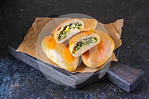 Homemade golden patties with green onion and egg on a black wooden board on a dark concrete background. Unsweetened pastries