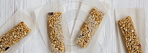 Homemade granola bars on baking sheet over white wooden surface, overhead view. Top view