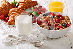 Homemade granola with berries, croissants, milk and juice closeu