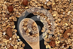 Homemade granola on black background, healthy breakfast of oatmeal muesli, nuts, seeds and dried fruit.